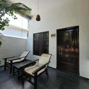 a porch with two chairs and a door at Agra Arugambay in Arugam Bay