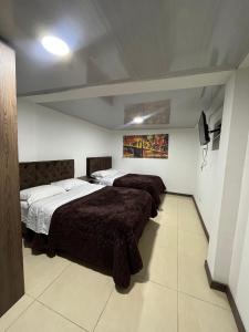 Amarena Hotel Boutique في مانيزاليس: غرفة نوم بسريرين في غرفة