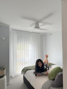 a woman laying on a bed in a bedroom at Owl+Oak in Castlemaine