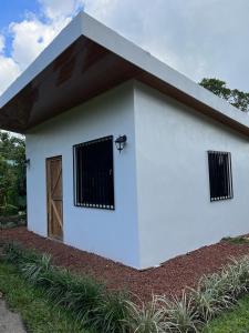 a small white building with a door and windows at Serenity Mountain in Poás