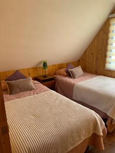 1 dormitorio con 2 camas y ventana en Cabaña Coñaripe, en Coñaripe