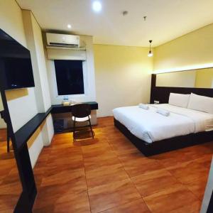 AZKA HOTEL Managed by Salak Hospitality في جاكرتا: غرفة نوم بسرير ومكتب وتلفزيون