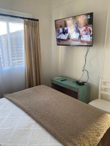 a bedroom with a bed and a tv on the wall at ALOJAMIENTO AVENIDA DEL MAR CABAÑA LA SERENA in La Serena