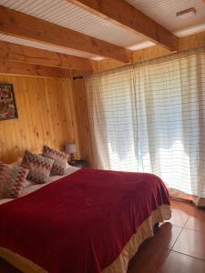 1 dormitorio con 1 cama grande en una habitación con paredes de madera en Cabaña Coñaripe, en Coñaripe