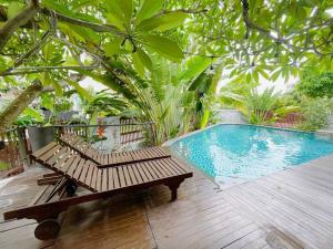 - une piscine avec deux bancs à côté d'une terrasse en bois dans l'établissement Maison Villa Orchid Phú Mỹ Hưng, à Hô-Chi-Minh-Ville