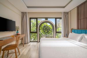 a bedroom with a bed and a desk and a window at Brilliant Majestic Hotel in Danang