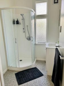 a white bathroom with a shower and a sink at Oamaru Villa in Oamaru