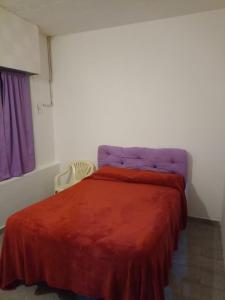 um quarto com uma cama com um cobertor vermelho em Lo de Nelly em Puerto Madryn