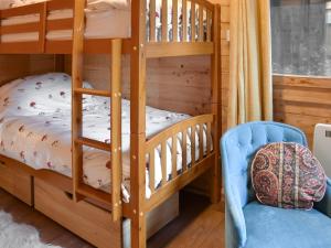 a bedroom with bunk beds and a blue chair at Algwen Cabin 