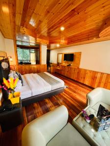 Himalayan Nature Walk Resort, Manali في مانالي: غرفة نوم بسرير واريكة في غرفة
