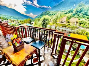 una mesa y sillas en un balcón con vistas en Himalayan Nature Walk Resort, Manali, en Manali