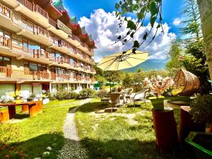 um pátio de um hotel com uma mesa e um guarda-chuva em Himalayan Nature Walk Resort, Manali em Manali