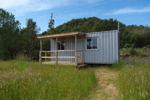 una pequeña casa gris en un campo de hierba en Ecoturismo Los Manzanos, en Pindapulli