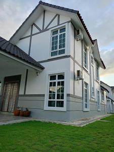 uma grande casa branca com um relvado verde em EV Sweet Holiday Homestay em Malaca