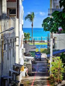 a street with a building and a palm tree and the ocean at 5 Loaves 2 Fish B&B in Hualien City