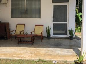um pátio com 2 cadeiras, uma mesa e uma porta em The Esence of Sri Lanka em Ahungalla