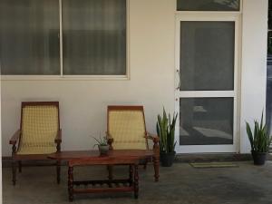 um pátio com 2 cadeiras, uma mesa e 2 janelas em The Esence of Sri Lanka em Ahungalla