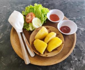 a plate of food with pineapple and salad and sauce at Grand Cory in Nusa Penida