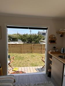 a kitchen with a door open to a yard at Kowhai Landing Beach Cabin in Otaki Beach