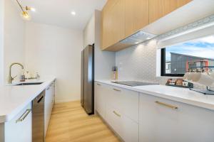 cocina con armarios blancos y ventana grande en Charming Urban Townhouse Getaway, en Auckland