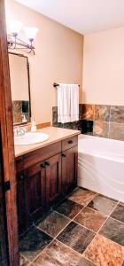 a bathroom with a sink and a tub and a mirror at Cozy 2 Bedroom 2 Bathroom Ski in Ski out Townhouse in Sun Peaks