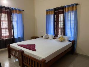 um quarto com uma cama grande e cortinas azuis em Anugraha Lotus Homestay em Varkala