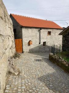 un edificio de piedra con techo rojo y entrada de piedra en BezerreiraComVida-O refúgio do monte en Bezerreira