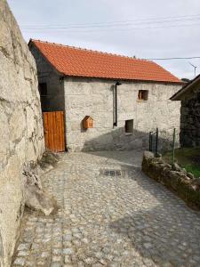 a stone building with a red roof and a stone driveway at BezerreiraComVida-O refúgio do monte in Bezerreira