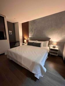 a bedroom with a large white bed with two lamps at New Modern Apartment near Mall in Guatemala