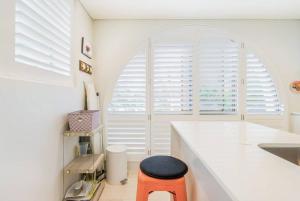 a kitchen with white counters and an orange stool at Balmoral Beach Beauty in Sydney