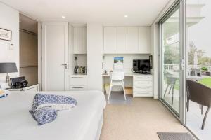 a bedroom with a bed and a desk and a kitchen at Balmoral Beach Beauty in Sydney