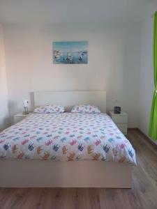a bedroom with a white bed with a bedspread on it at Apartment Perica - 10 m from sea in Postira