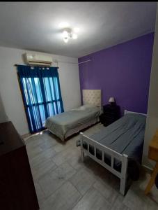 1 Schlafzimmer mit 2 Betten und einer lila Wand in der Unterkunft Casa para el festival in Colonia Caroya