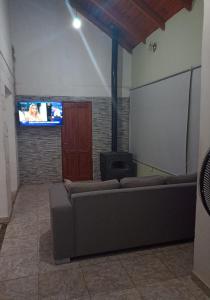 a living room with a couch and a flat screen tv at Casa para el festival in Colonia Caroya