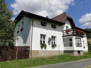 una casa blanca con flores en las ventanas en Romanówka, en Ołdrzychowice Kłodzkie