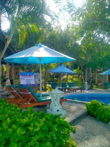 - un parasol et des chaises à côté de la piscine dans l'établissement Coral Bay Bungalows Amed Bali, à Amed