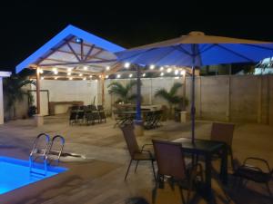 eine Terrasse mit einem Tisch und Stühlen sowie einem Pool in der Nacht in der Unterkunft Casas Dñ Juanita in Jacó