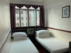 Dos camas en una habitación con dos ventanas. en Hang Fung Hostel, en Hong Kong