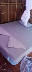 a bed with purple sheets on top of it at Efenli Arnes homestay in Yennanas Besir