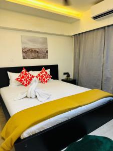 1.5BR Service apartment in BKC by Florastays في مومباي: غرفة نوم بسرير كبير ومخدات حمراء وصفراء