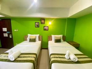 two beds in a room with green walls at Chinda Boutique Hotel - SHA Certified in Chiang Mai