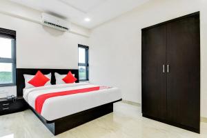 1 dormitorio con 1 cama con almohadas rojas en Flagship V&s Hotel, en Pimpalgaon