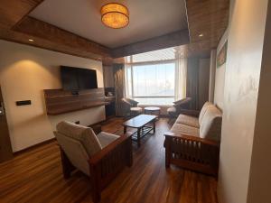 uma sala de estar com um sofá e cadeiras e uma televisão em Gakhil Boutique Hotel em Darjeeling