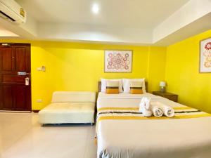 two beds in a room with yellow walls at Chinda Boutique Hotel - SHA Certified in Chiang Mai