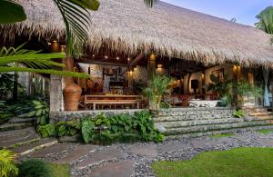 a resort with a thatched building with a bench and stairs at Stone House in Ubud