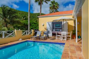 克里斯琴斯特德的住宿－Seaview Palms Villa - St Croix USVI，一个带桌椅和遮阳伞的游泳池