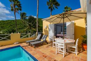 un patio con mesa, sillas y sombrilla en Seaview Palms Villa - St Croix USVI, en Christiansted