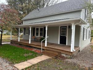 a small white house with a wooden porch at Crabapple Cottage in Hesston