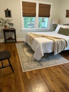 a bedroom with a bed and a rug and two windows at Crabapple Cottage in Hesston