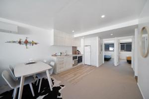 a white kitchen with a table and a dining room at Blackrock Apartments Queenstown in Queenstown